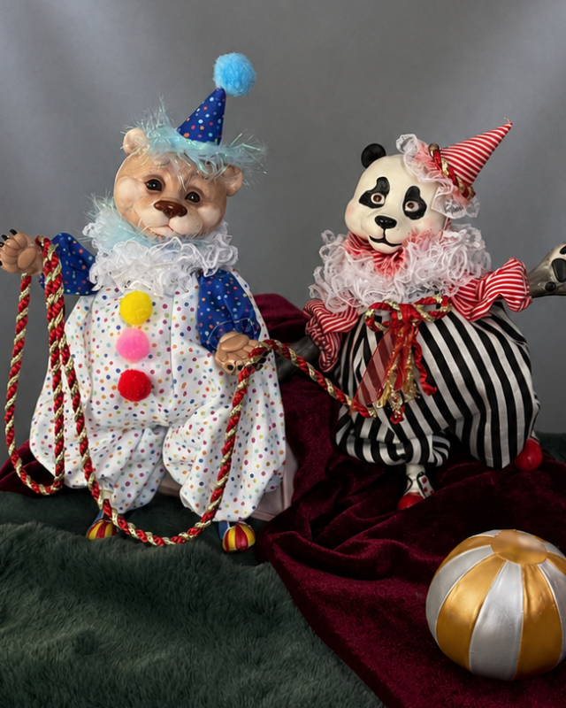 Two toy bears dressed as colourful clowns sit together, holding braided ropes against a grey backdrop.